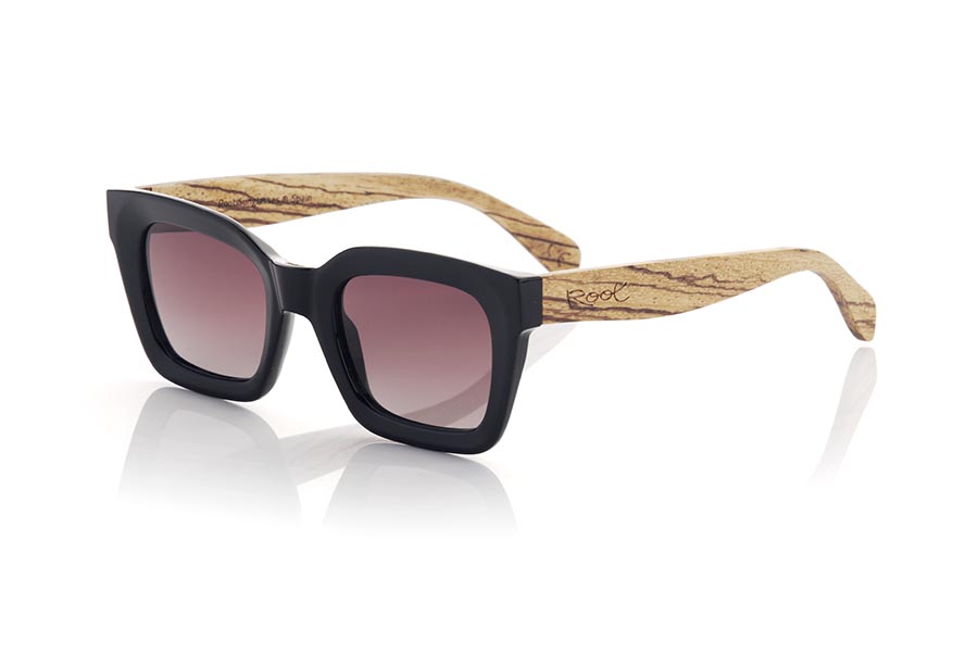 Gafas de Madera Natural de Walnut modelo OONA. Las gafas de sol OONA son el accesorio perfecto para completar tu look. Con una montura frontal en color negro satinado de forma cuadrada y esquinas redondeadas, estas gafas tienen un toque moderno y sofisticado. Las varillas anchas son de madera de zebrano, creando un hermoso contraste de color. Estas gafas son ideales para mujeres que buscan algo diferente y único. Además, montan lentes marrón gradient que ofrecen protección contra los rayos UV. Siéntete elegante y protegida del sol con las gafas de sol OONA. | Root Sunglasses® 